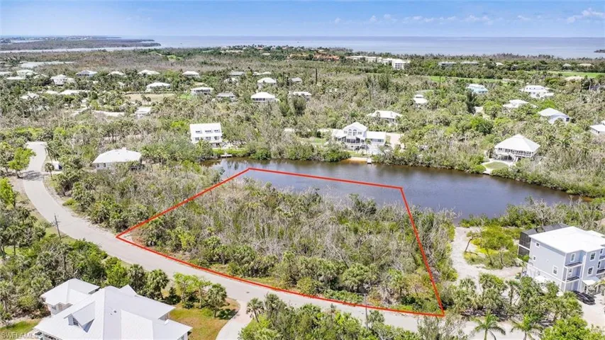 Aerial view of residential area with property parcel outlined and a nearby body of water