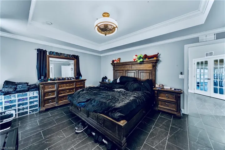 Bedroom featuring marble finish floor, a tray ceiling, and crown molding