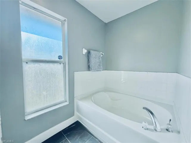 Full bathroom with a garden tub and baseboards