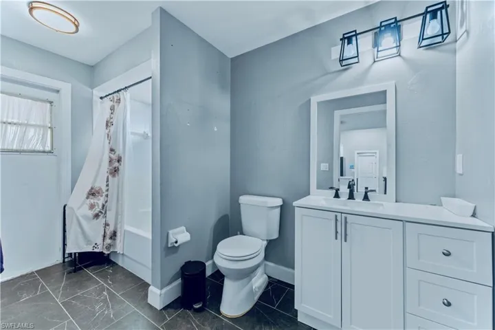 Bathroom featuring shower / bath combo, vanity, baseboards, and toilet