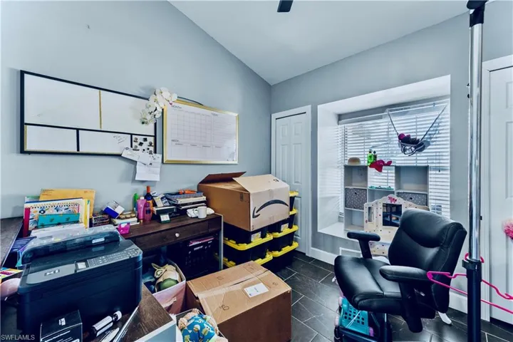 Home office with dark tile patterned flooring and vaulted ceiling
