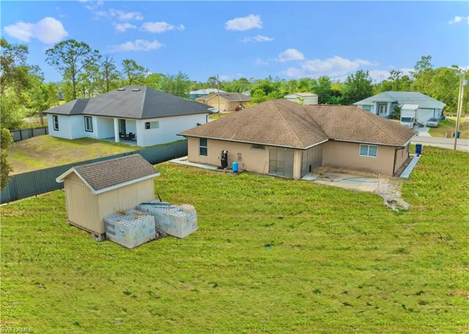 Back of house featuring a yard, an outdoor structure, fence, and a storage unit