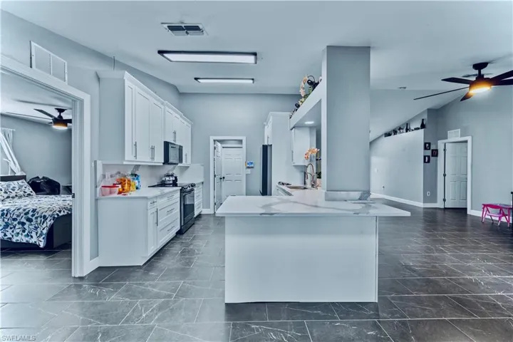 Kitchen with black microwave, visible vents, ceiling fan, electric stove, and a sink