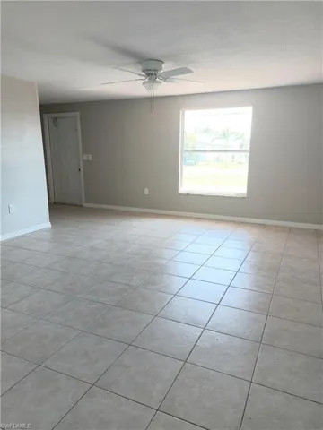 Spare room with a ceiling fan, light tile patterned flooring, and baseboards