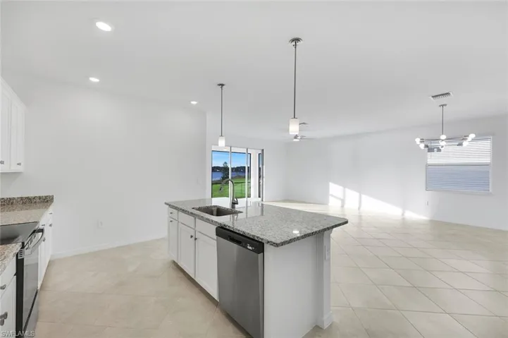 Kitchen with stainless steel appliances, pendant lighting, white cabinets, light stone countertops, and recessed lighting