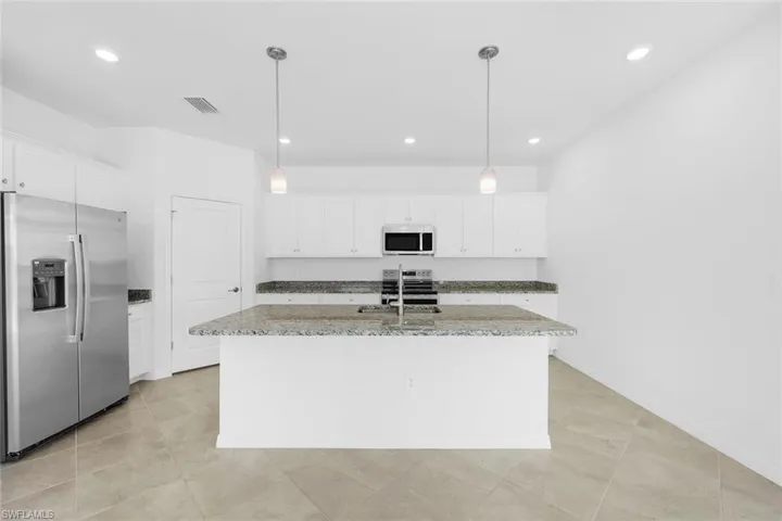 Empty room featuring a water view, ceiling fan, and light tile patterned floors