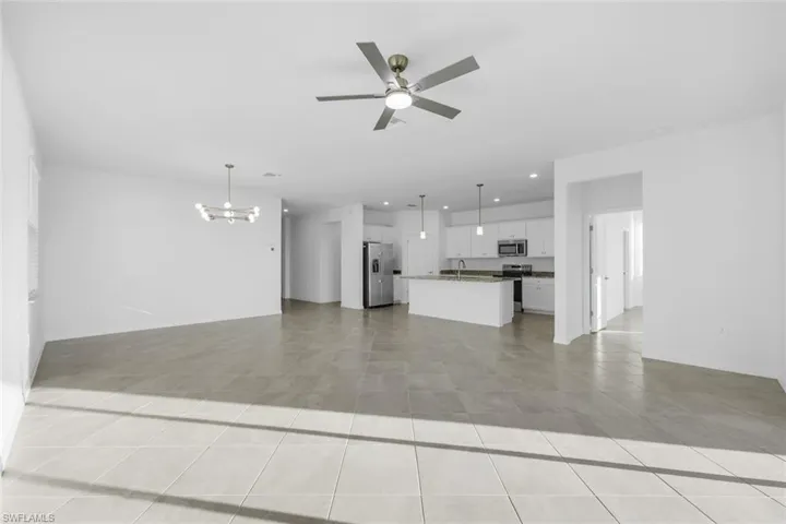 Spare room featuring a water view, a ceiling fan, a chandelier, and light tile patterned flooring