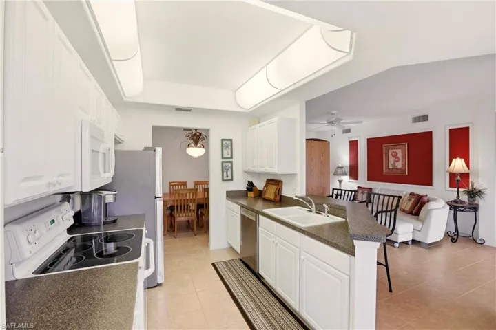 Kitchen with slate countertops, stainless steel appliances, white cabinets, a breakfast bar area, and light tile patterned flooring