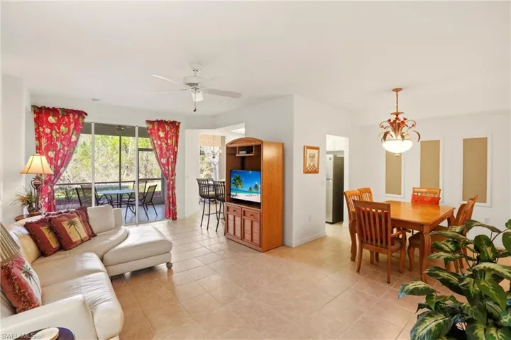 Living room featuring light tile patterned flooring, a ceiling fan, and a chandelier