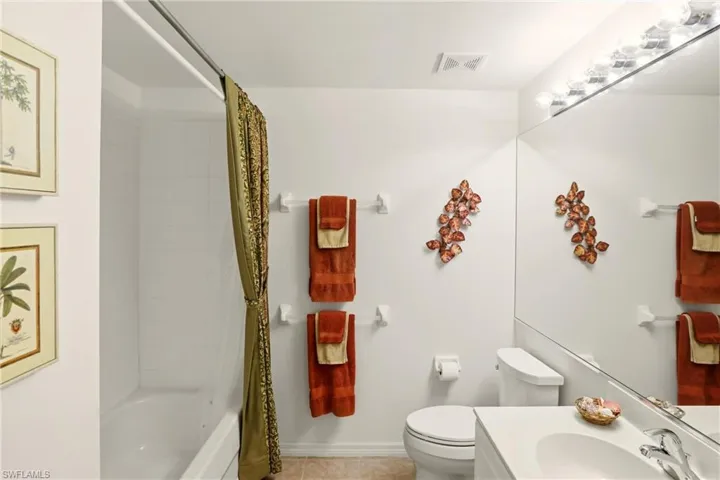 Bathroom with shower / bath combo with shower curtain, vanity, and tile patterned flooring