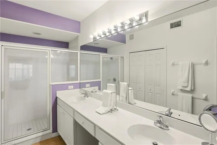 Bathroom featuring a double vanity, and shower stall