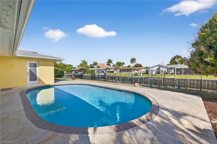 View of swimming pool with patio surround, a residential view, and a fenced backyard