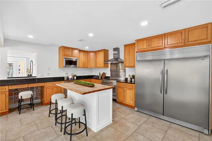 Kitchen with built in appliances, wood counters, a breakfast bar, recessed lighting, and ornamental molding