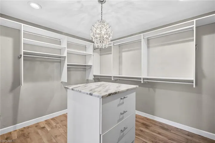 Walk in closet featuring light wood-style flooring and a chandelier