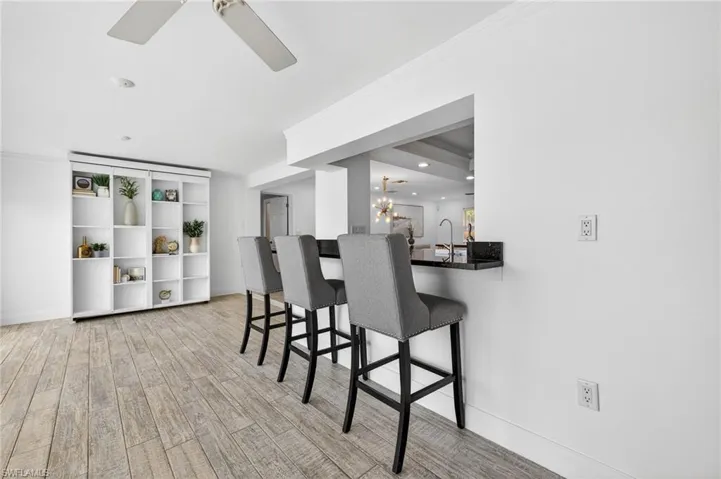Kitchen featuring a kitchen breakfast bar, ornamental molding, ceiling fan, light wood-type flooring, and a chandelier