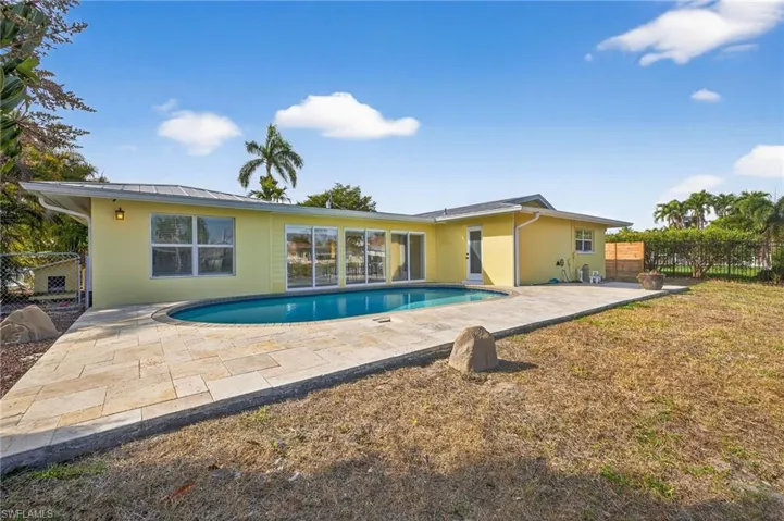 Rear view of house featuring stucco siding, a patio area, and a metal roof