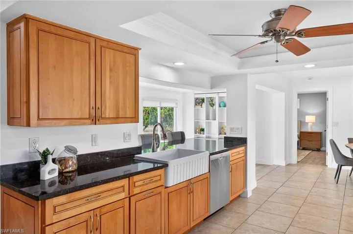 Kitchen with dark stone countertops, recessed lighting, a ceiling fan, stainless steel dishwasher, and wood finish cabinetry