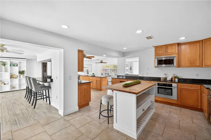 Kitchen featuring a breakfast bar, a ceiling fan, a peninsula, crown molding, and wood finish cabinetry