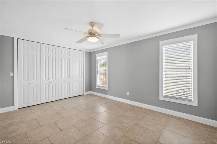 Unfurnished bedroom with ornamental molding, a closet, and ceiling fan