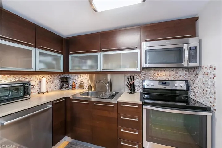 Kitchen featuring tasteful backsplash, sink, dark brown cabinets, and appliances with stainless steel finishes