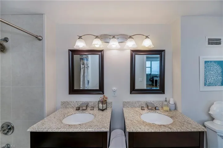 Full bathroom /dual vanities, toilet, and tiled shower / bath combo