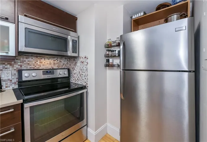 Kitchen modern cabinets, stainless steel appliances, light hardwood / wood-style flooring, and tasteful backsplash