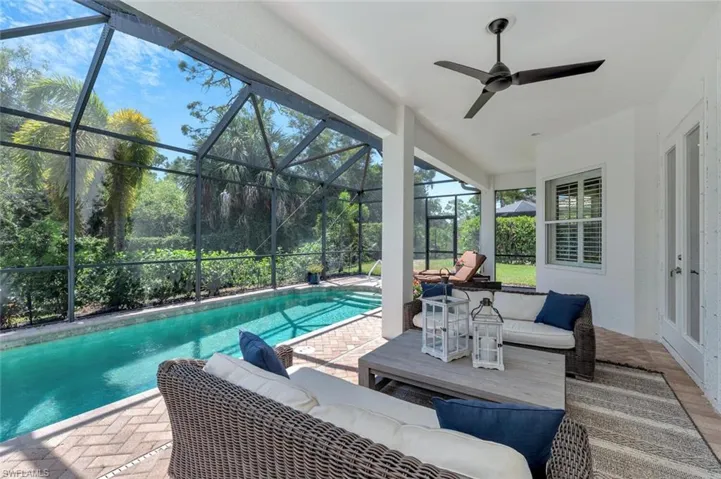 Outdoor pool with glass enclosure, an outdoor living space, ceiling fan, and a patio area