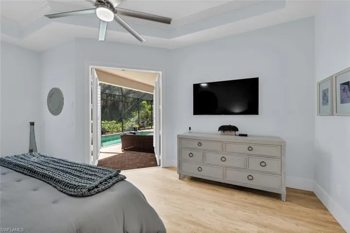 Bedroom with baseboards, light wood-style flooring, a raised ceiling, and access to outside
