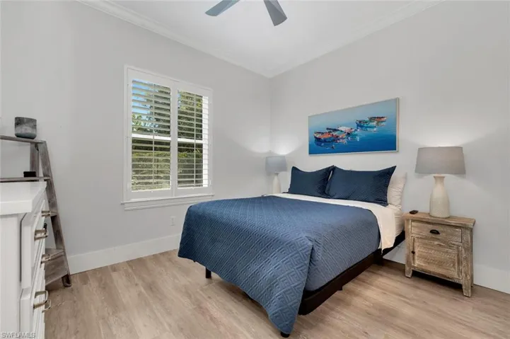 Bedroom featuring baseboards, crown molding, light wood-style floors, and a ceiling fan