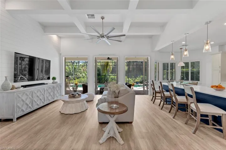 Living area featuring light wood finished floors, visible vents, ceiling fan, and coffered ceiling