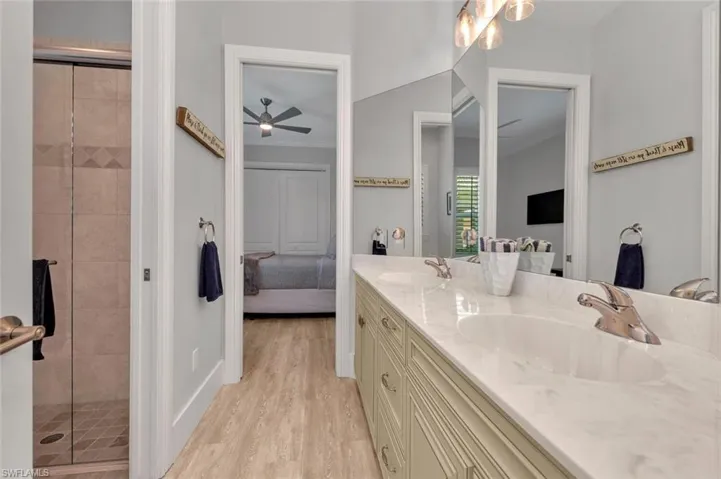Ensuite bathroom with ensuite bathroom, ornamental molding, a sink, and a shower stall
