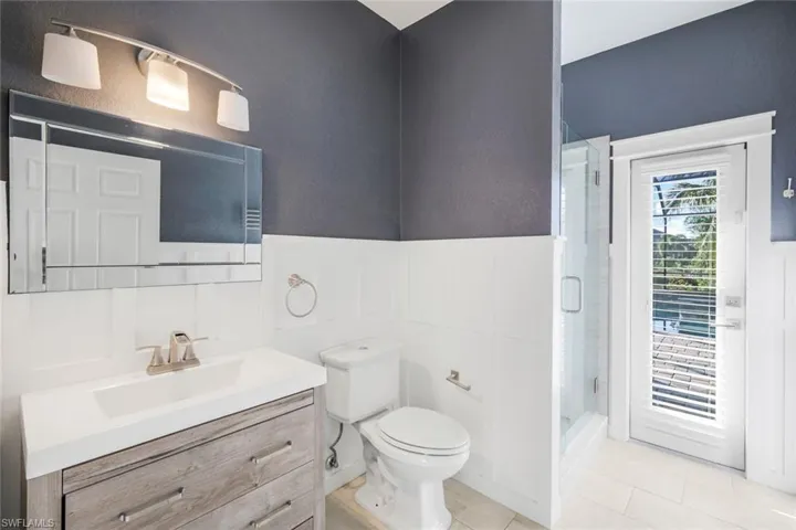 Full bathroom featuring tile patterned flooring, a wainscoted wall, toilet, a stall shower, and vanity