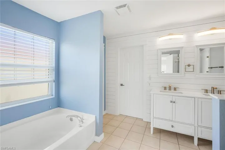 Full bathroom with a bath, a healthy amount of sunlight, visible vents, and a sink