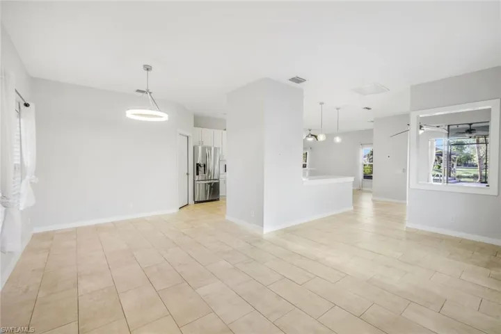 Unfurnished living room with a ceiling fan, visible vents, and baseboards