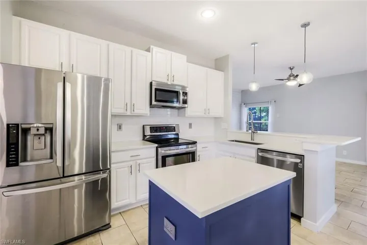 Kitchen with tasteful backsplash, ceiling fan, light countertops, white cabinets, and stainless steel appliances
