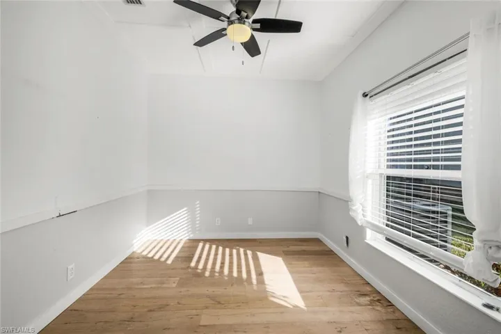 Unfurnished room featuring baseboards, attic access, a ceiling fan, and hardwood / wood-style flooring