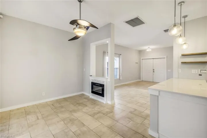 Unfurnished living room featuring a fireplace, a ceiling fan, visible vents, and baseboards