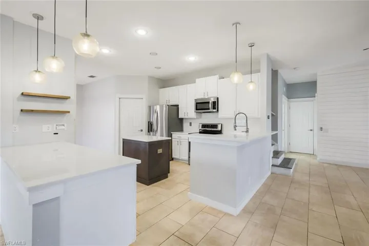 Kitchen featuring backsplash, a center island, stainless steel appliances, a peninsula, and light countertops