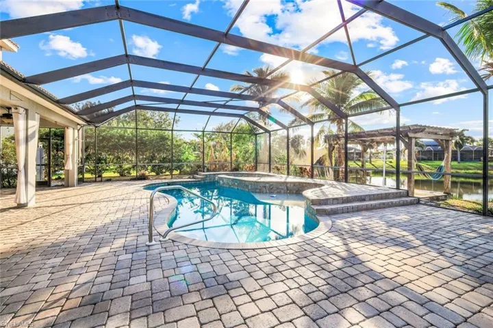 View of pool with a patio, a pool with connected hot tub, a lanai, and a water view