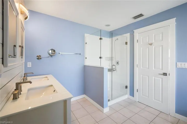 Bathroom featuring tile patterned floors, baseboards, a shower stall, and a sink