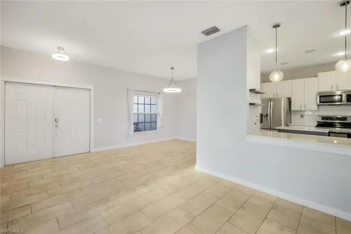Kitchen featuring pendant lighting, light countertops, decorative backsplash, white cabinets, and stainless steel appliances