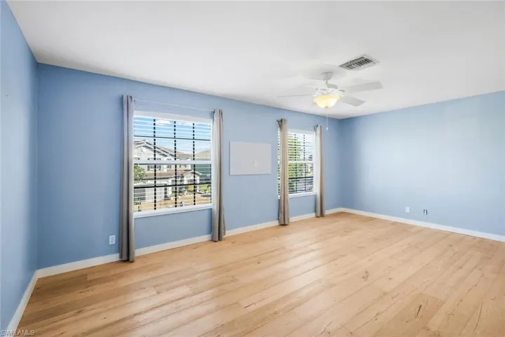 Unfurnished room featuring ceiling fan, wood finished floors, visible vents, and baseboards