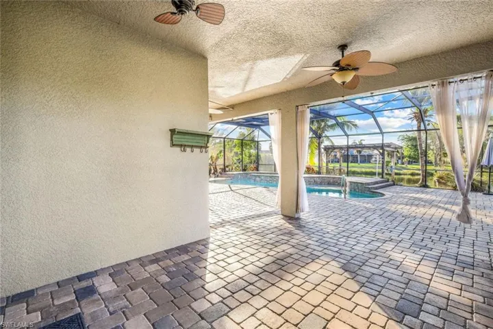 View of patio featuring glass enclosure, an outdoor pool, and a ceiling fan