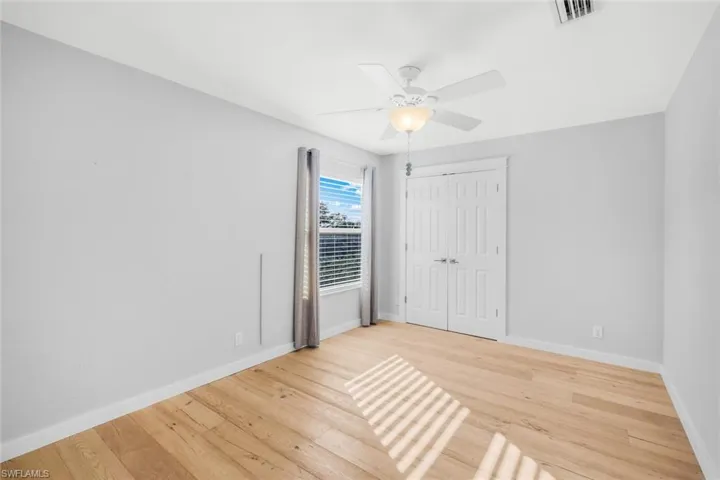 Unfurnished bedroom featuring visible vents, baseboards, wood finished floors, and a ceiling fan