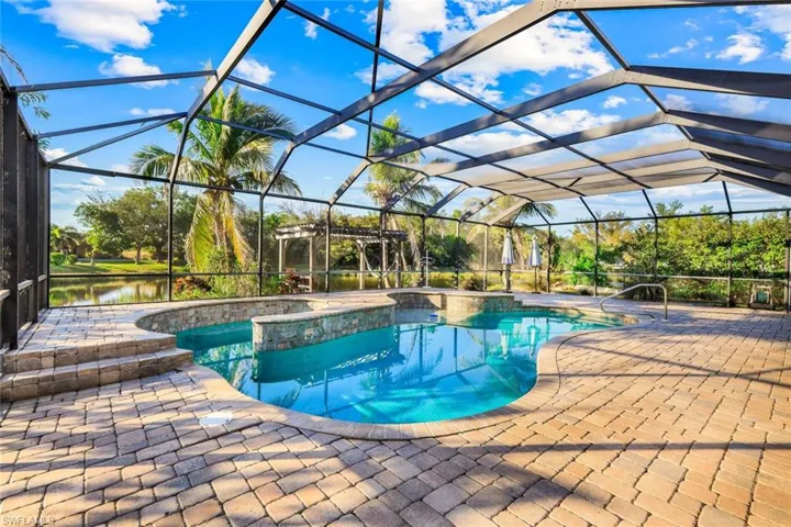 Pool featuring glass enclosure, a patio, and a water view