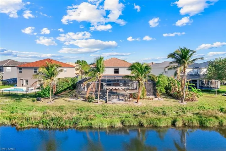 Back of property with a residential view, glass enclosure, and a water view