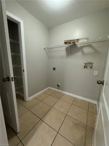 Laundry room with light tile patterned flooring, hookup for an electric dryer, and washer hookup