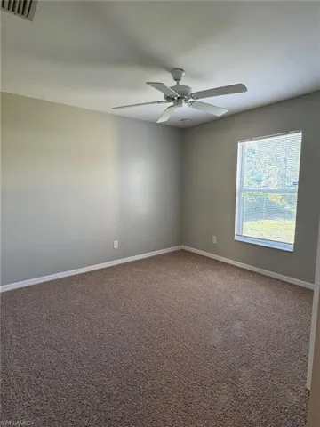 Empty room featuring carpet flooring and a ceiling fan