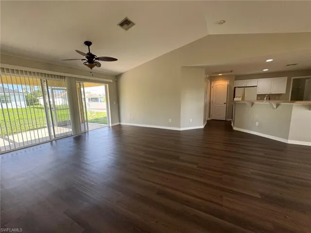 Unfurnished living room with vaulted ceiling, dark wood-style flooring, and ceiling fan