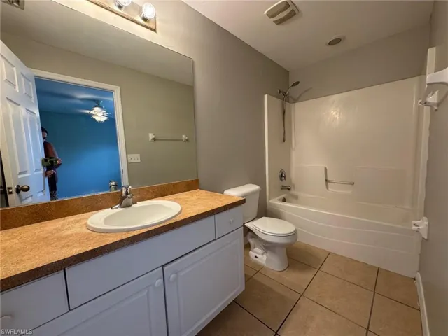 Bathroom featuring light tile patterned flooring, shower / tub combination, and vanity